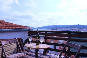 Eine Terrasse mit Tisch, Stühlen, einer Weinflasche und zwei Gläsern.