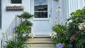 A white house with a white door and a window above it. There are steps leading up to the door, and potted plants on either side. - Attic studio in the Geteviertel - close to the city, trade fair, university, stadium and Weser cycle path (Schwachhausen)
