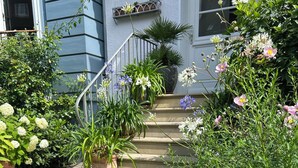 A residential property with a staircase leading to a door, surrounded by lush greenery and flowering plants. - Attic studio in the Geteviertel - close to the city, trade fair, university, stadium and Weser cycle path (Schwachhausen)