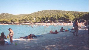 Una platja plena de gent que pren el sol i nedant.