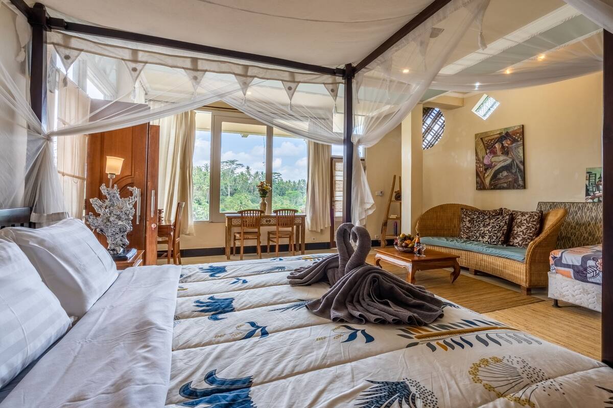 Ein Schlafzimmer mit Himmelsbett, einer Couch, einem Essbereich und einem Gemälde an der Wand.
