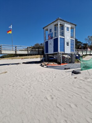 Ett livräddartorn med en blå och vit fasad, placerat på en sandstrand.