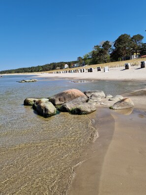 Uma praia com águas cristalinas, grandes rochas e uma faixa de areia.