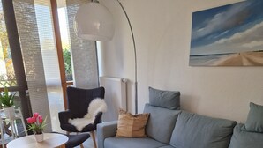 En moderne stue med en grå sofa, en sort lænestol, et lille rundt bord og en sort måtte.