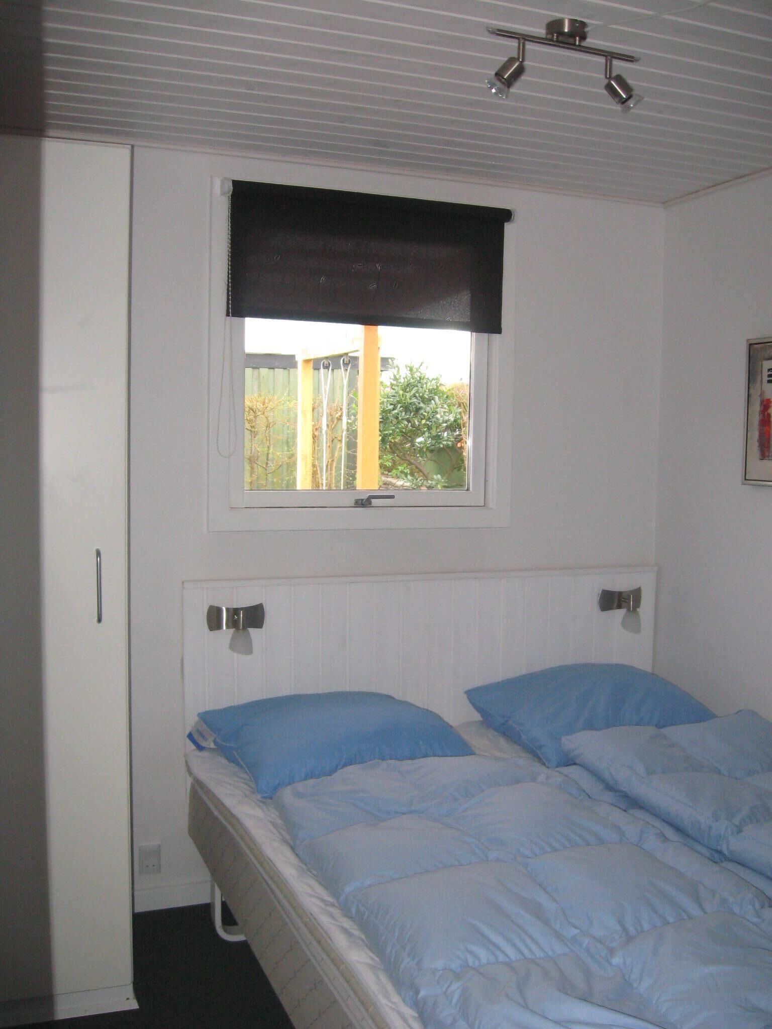 A bedroom with a single bed, a window with a black blind, and a radiator.