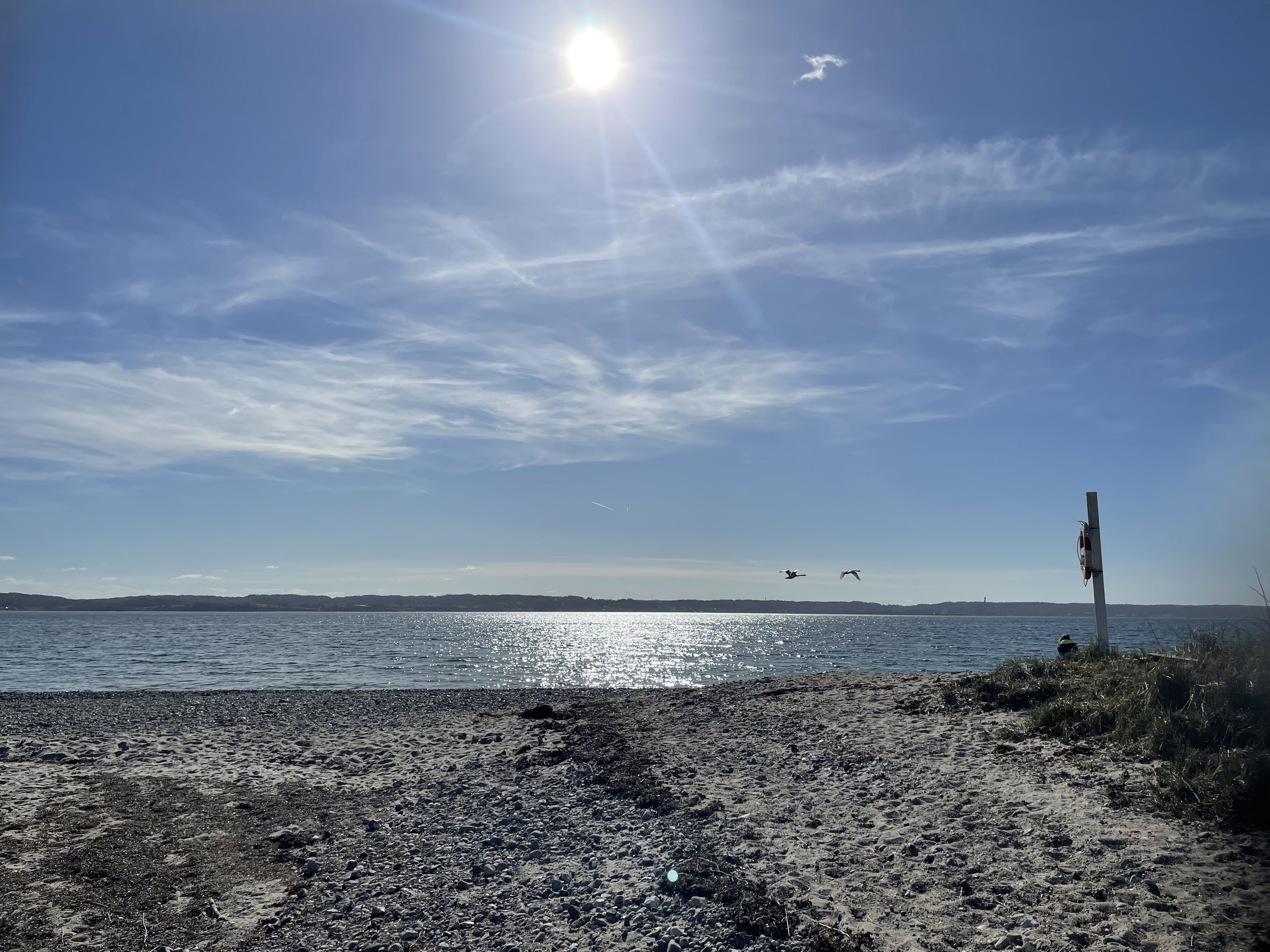 A beach with pebbles and a clear sky.