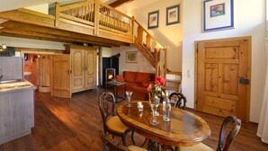 A spacious kitchen with wooden cabinets, a dining area with a wooden table and chairs, and a staircase leading to an upper level.