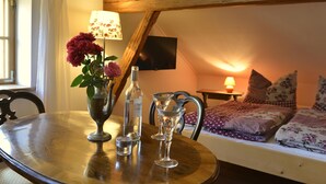 A cozy room with a wooden table, a vase with flowers, a bottle, and a lamp.