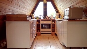 Eine kleine Küche mit Holzausstattung, einem Einbauofen und einer Arbeitsplatte.