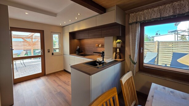 Una cocina moderna con una isla integrada, suelo de madera y vistas al patio exterior.