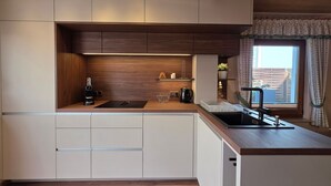 Una cocina moderna con electrodomésticos integrados, armarios de madera y un ventanal con cortinas.
