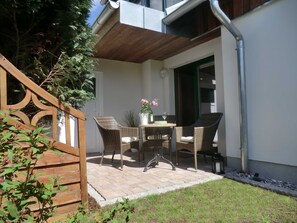 A patio with wicker furniture, a table with a vase and glass, and a wooden fence. - Apartment Knurrhahn - Apartment Knurrhahn (Karlshagen)