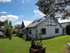 Une maison de plain-pied avec un toit en pente, un balcon et une grande fenêtre.