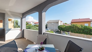 A balcony with a table, chairs, and a potted plant.