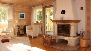 A cozy room with a fireplace, wicker baskets, and a rocking chair. - Idyllic lakeside location, luxury furnishings - sauna, boat, canoe, WLAN, 3 bedrooms. (Nybro S)