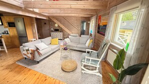 A cozy cabin interior with a sofa, armchair, and dining area. - Idyllic lakeside location, luxury furnishings - sauna, boat, canoe, WLAN, 3 bedrooms. (Nybro S)