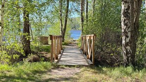 A wooden bridge leading to a body of water surrounded by trees. - Idyllic lakeside location, luxury furnishings - sauna, boat, canoe, WLAN, 3 bedrooms. (Nybro S)