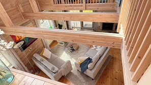A multi-level wooden cabin with a loft bedroom, a living area with a sofa and coffee table, and a fireplace. - Idyllic lakeside location, luxury furnishings - sauna, boat, canoe, WLAN, 3 bedrooms. (Nybro S)
