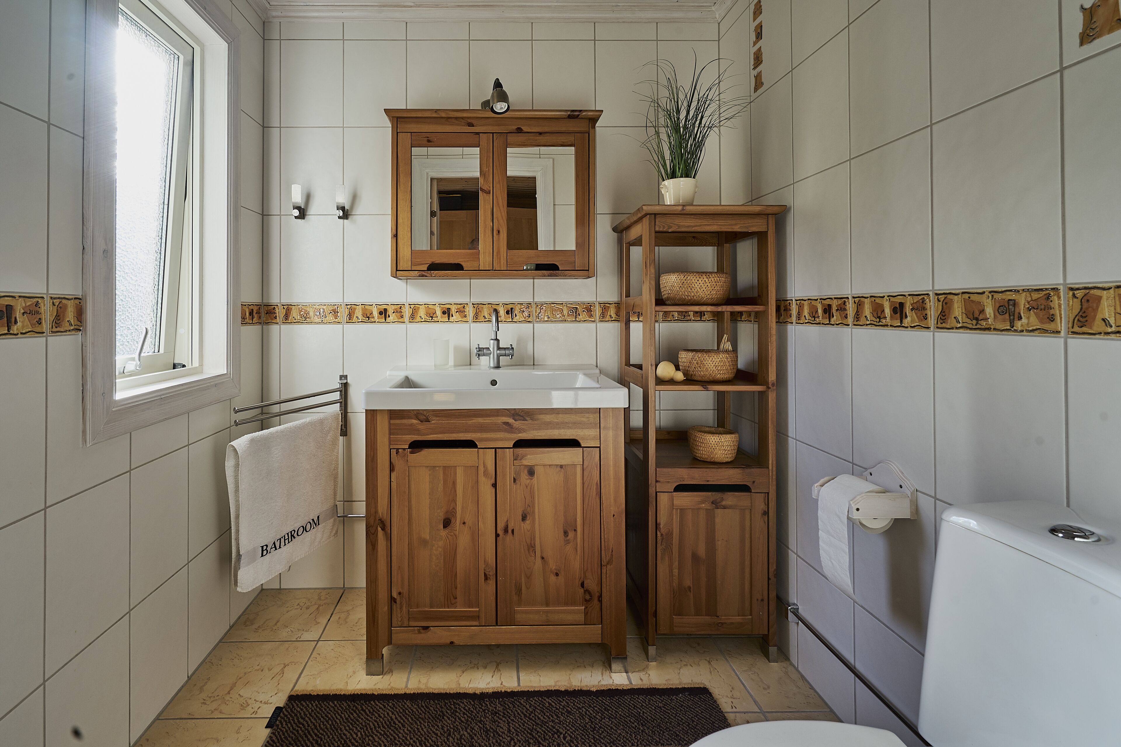 Une salle de bain avec un meuble-lavabo en bois, un lavabo blanc, un miroir et des toilettes.