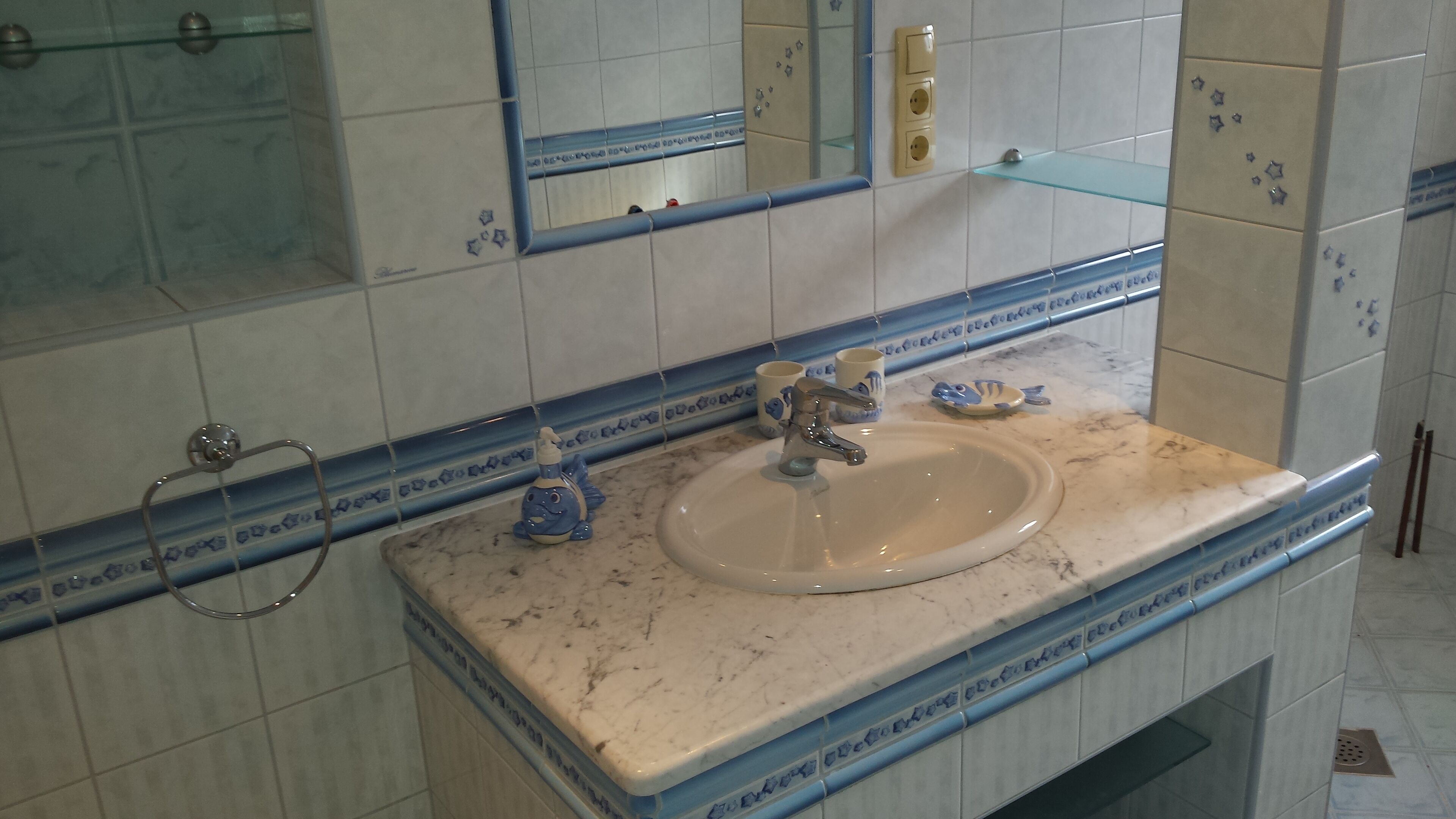 A bathroom with a sink, mirror, and tiled walls.