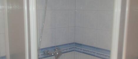 Un espacio de ducha pequeño y cerrado, con azulejos blancos y detalles azules.