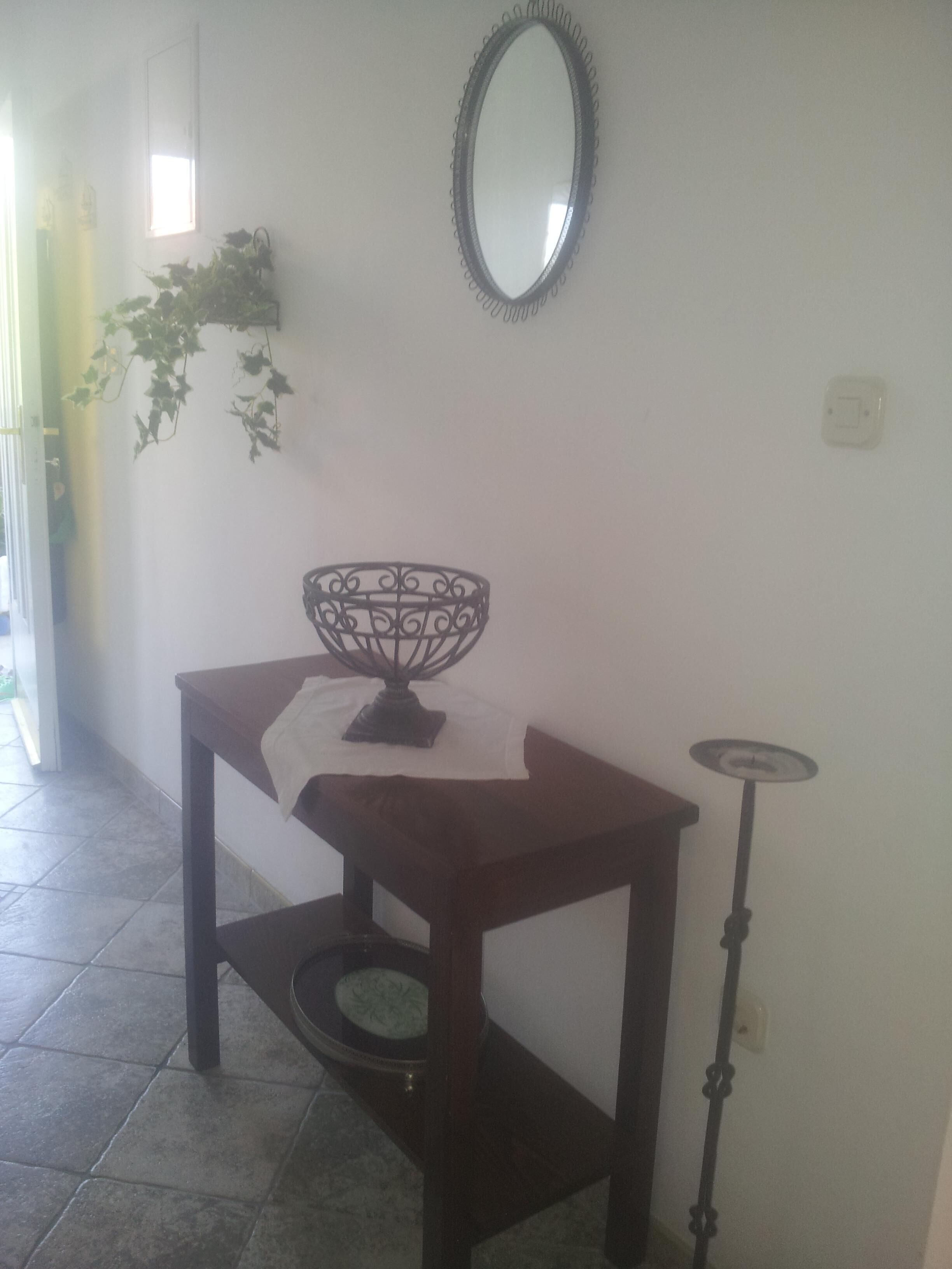 A corner with a wooden table, a decorative bowl, a mirror, and a floor lamp.