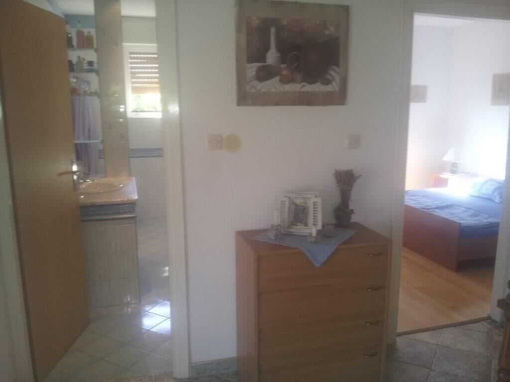 Une pièce avec une commode en bois, un lit et un tableau accroché au mur.