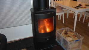 Uma lareira a lenha em um quarto com uma mesa de jantar e cadeiras.