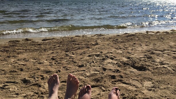 Uma praia com vista clara para o oceano e terra ao longe.