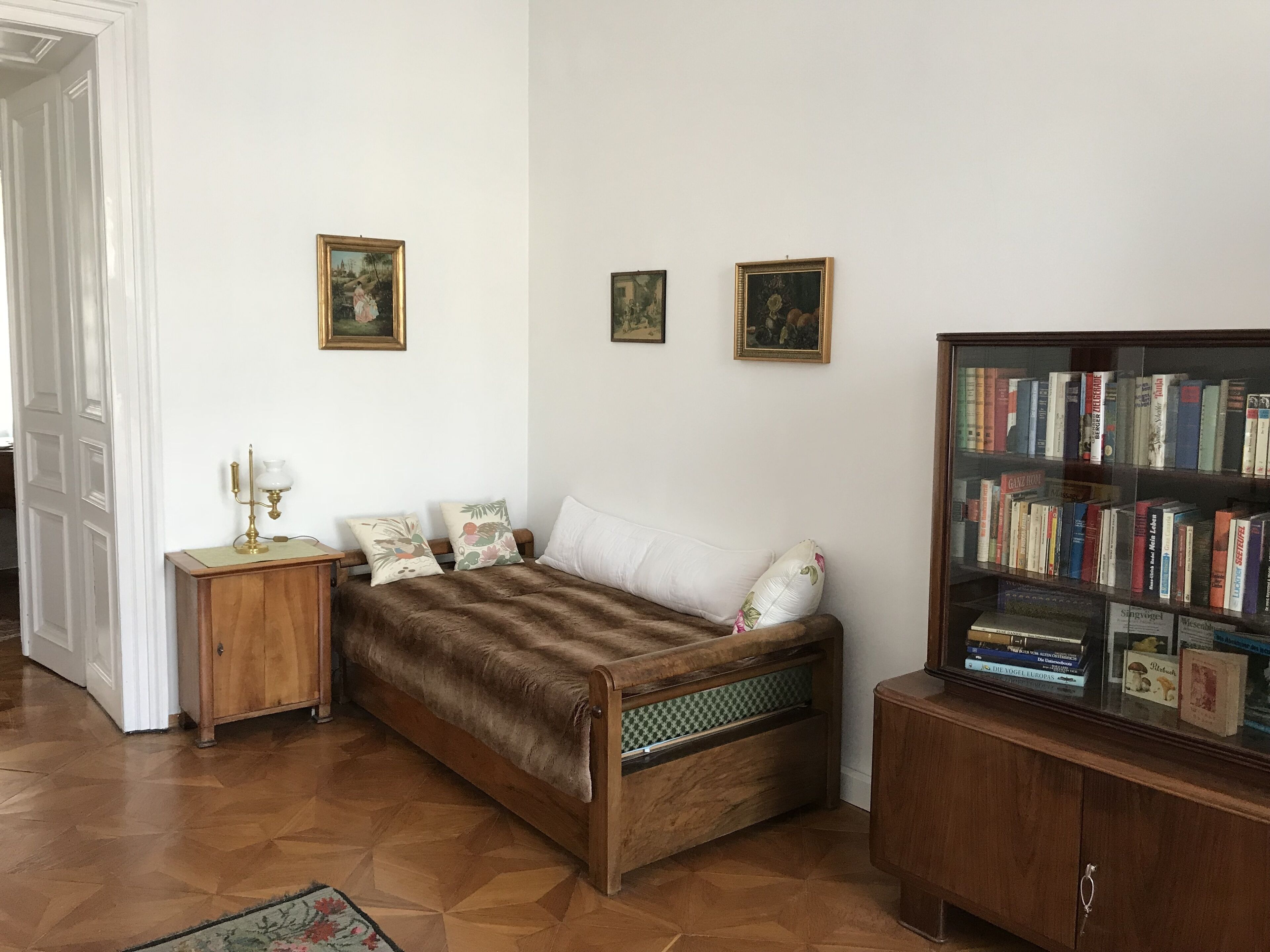A room with a wooden bed, a nightstand, a bookshelf, and a door.