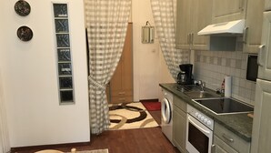 Une cuisine compacte équipée d’un lave-linge, d’une machine à café et d’un four à micro-ondes.