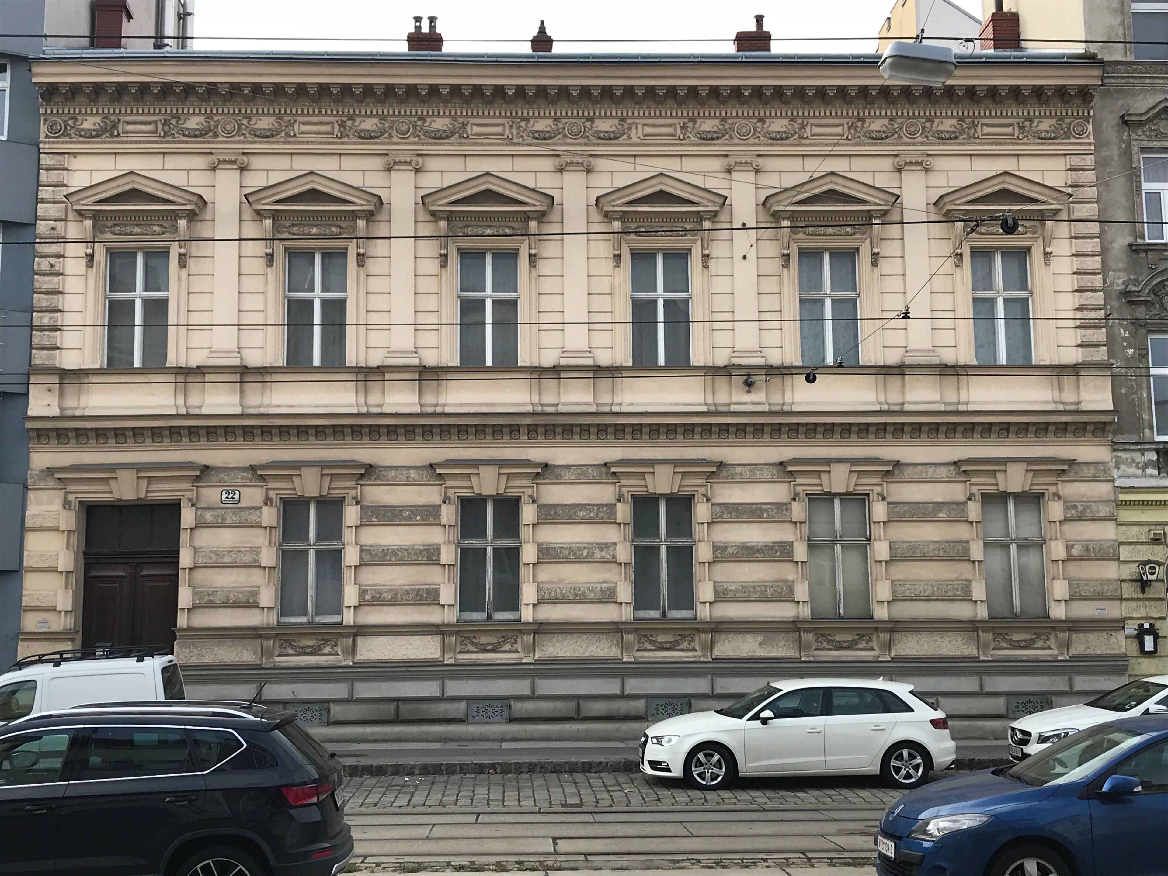 A multi-story building with a classical architectural style, featuring a symmetrical facade with evenly spaced windows and decorative moldings.