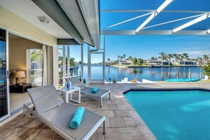 A pool area with lounge chairs and a view of a body of water.