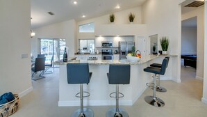 Une cuisine moderne dotée d’un îlot central, de tabourets de bar et d’un coin repas avec des chaises.