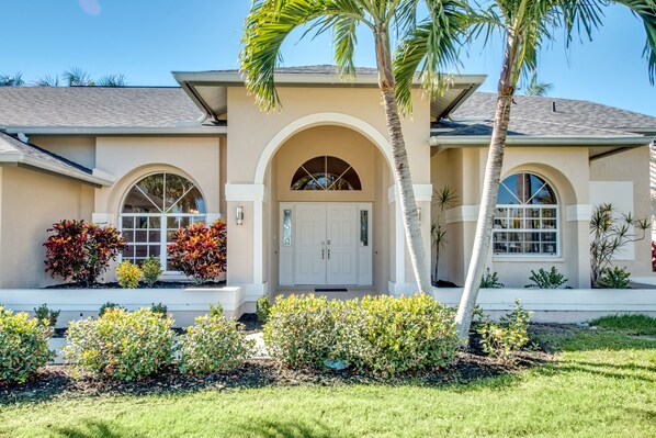 A two-story house with a beige facade, arched windows, and a front porch.