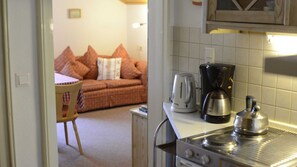 A kitchenette with a stove, coffee maker, and kettle. - Double / Breakfast With View to Sorgschrofen - Landhaus Windrose (Jungholz)