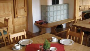 Ein Essbereich mit Holzmöbeln, einem zentralen Tisch mit roter Tischdecke und einem alten Herd.
