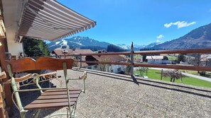 A balcony with a wooden bench, a metal railing, and a view of a mountain landscape.