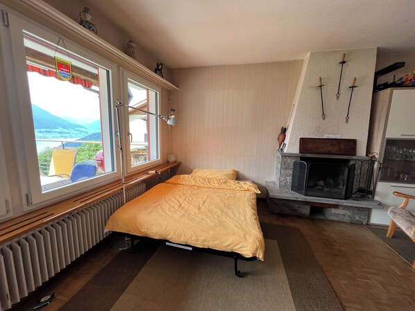Une chambre à coucher avec un lit, une fenêtre donnant sur un beau paysage, une cheminée et un radiateur.
