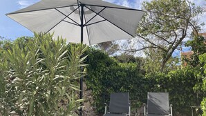 Een terras met twee loungestoelen en een grote parasol.