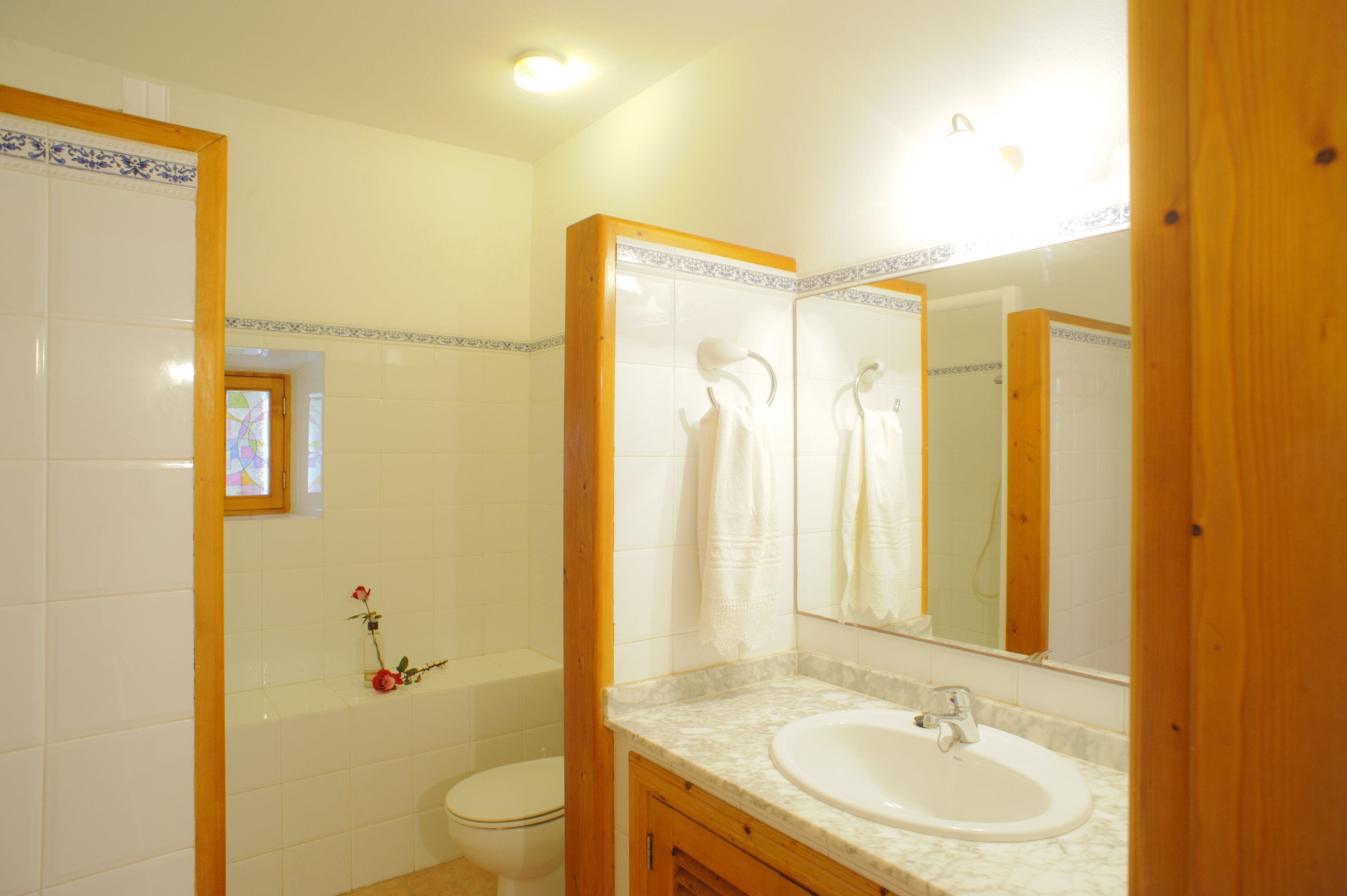 Une salle de bain avec un lavabo blanc, un miroir et des toilettes.