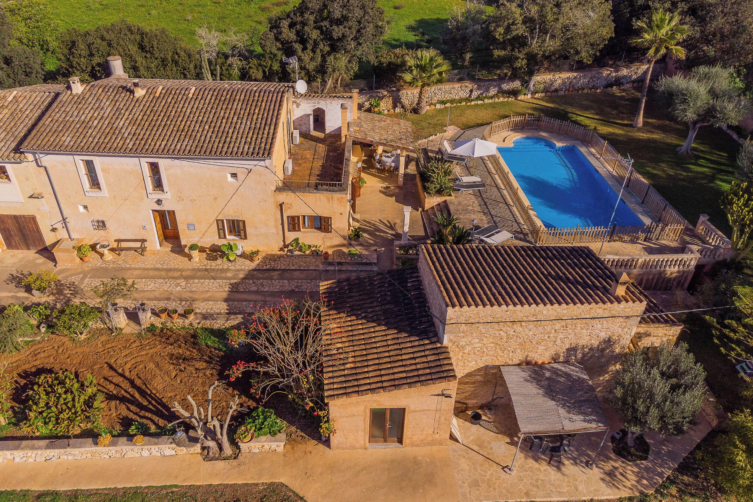 A large villa with a swimming pool, terracotta roof tiles, and a garden.
