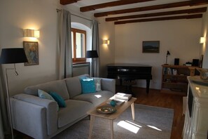 A living room with a sofa, a piano, a coffee table, and a bookshelf. - Holiday house Enke, Germany (Miesbach)