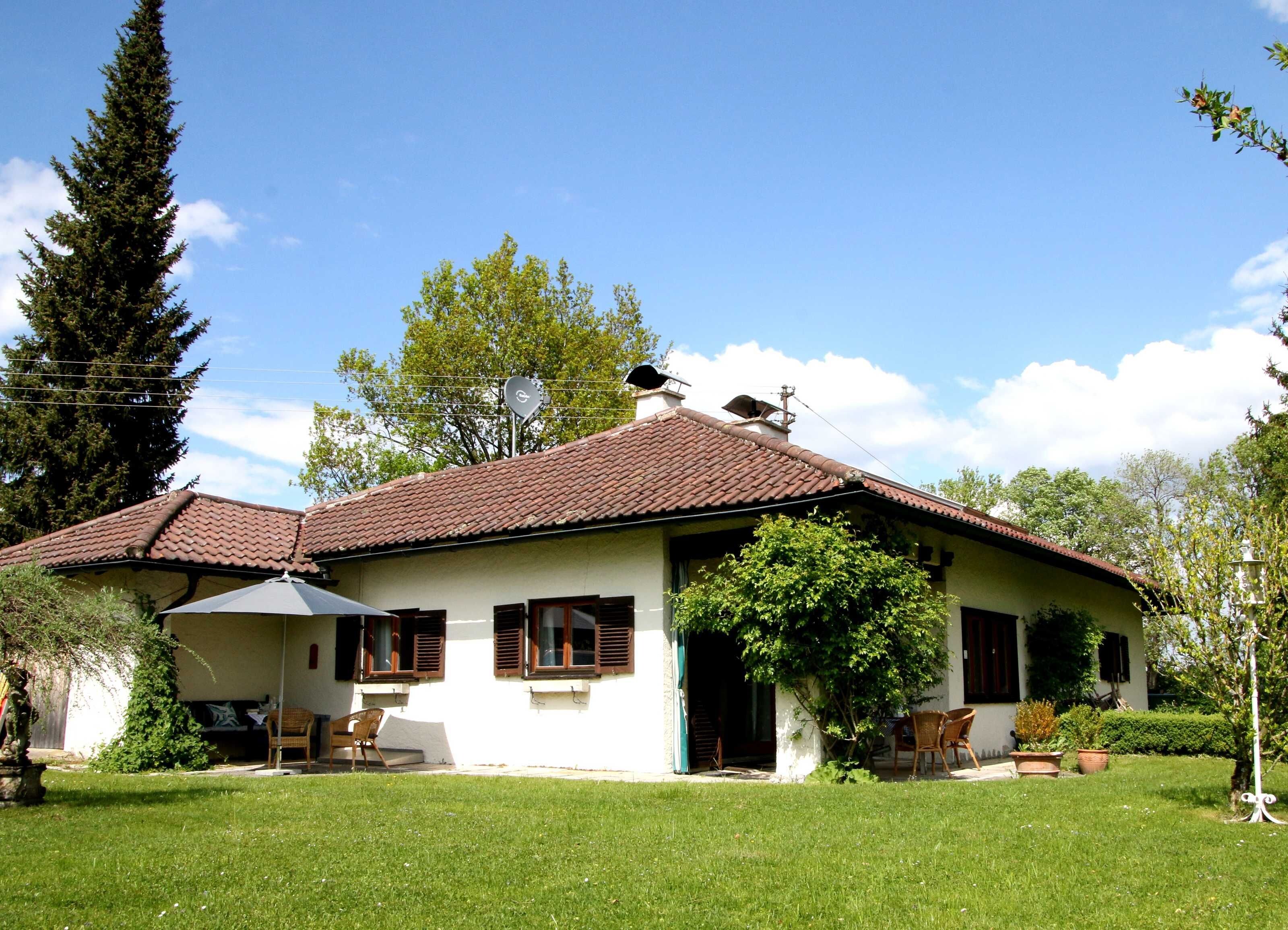 A house with a tiled roof, a covered porch, and a well-maintained lawn.