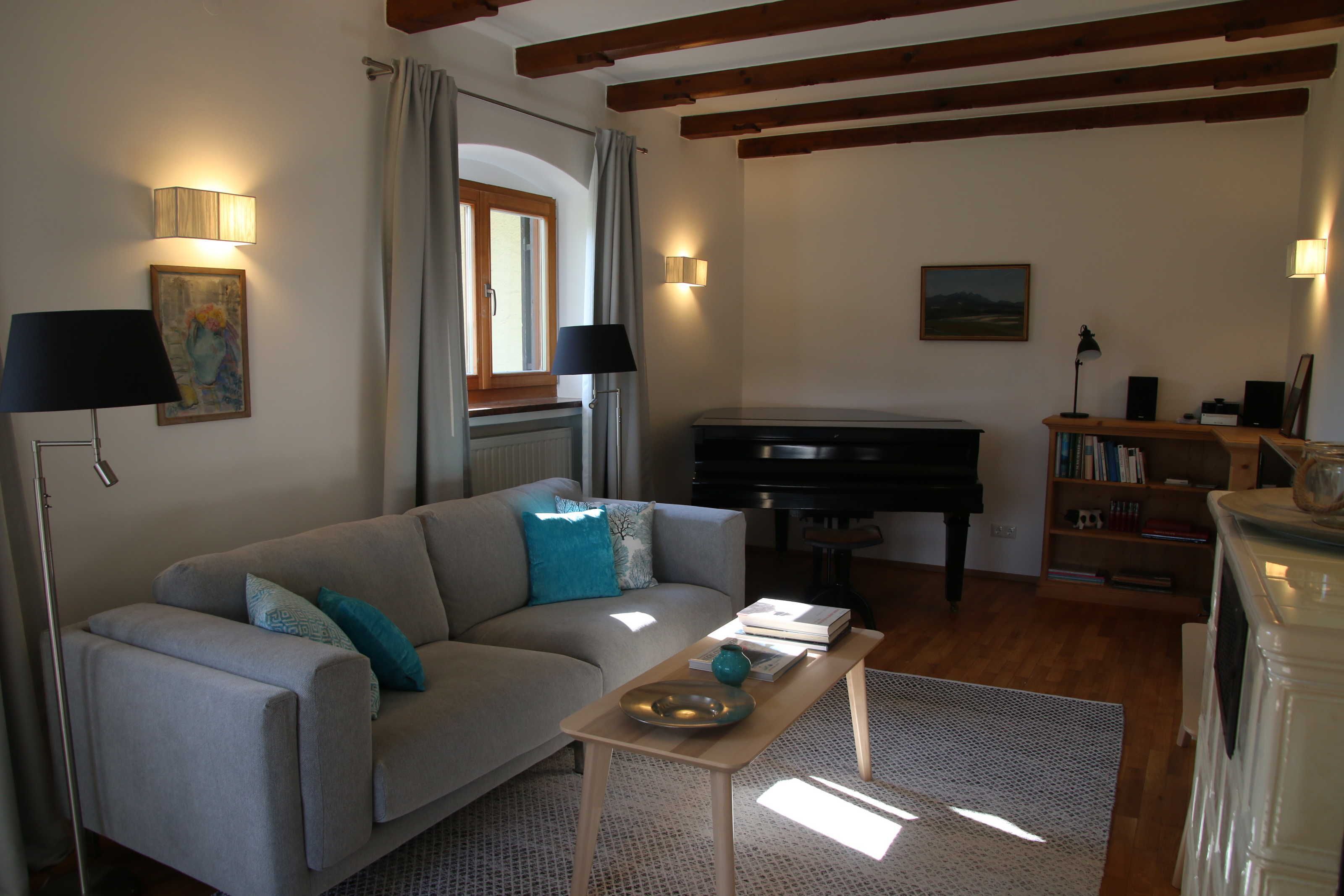 Ein Wohnzimmer mit Sofa, Klavier, Couchtisch und Bücherregal.