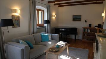 Ein Wohnzimmer mit Sofa, Klavier, Couchtisch und Bücherregal.
