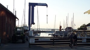Een jachthaven met boten afgemeerd, een kraan en een gebouw met een bord.