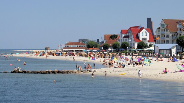 Een strand met gebouwen, tenten en mensen.
