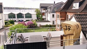 Een balkon met tuinmeubilair, een uitzicht op een jachthaven en woongebouwen op de achtergrond.