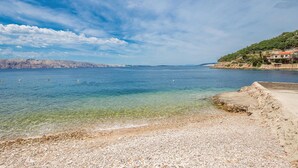 A coastal scene with clear water, pebbly beach, and distant rocky cliffs. - Lovely apartment in Stinica with house sea view (Stinica)